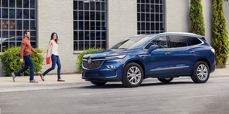 A couple walks towards their Blue Buick Enclave