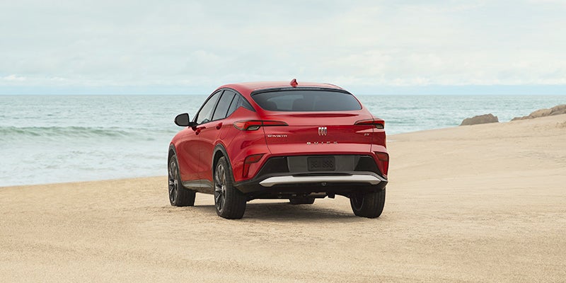 A red Buick Enclave, parked on a beach.