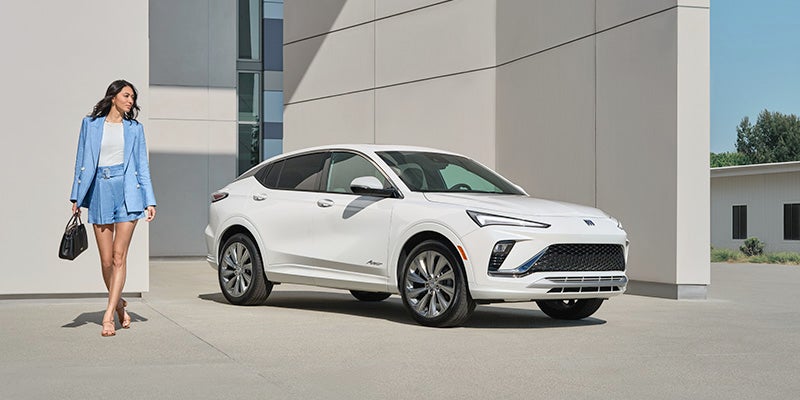 A woman walks away from a white Buick Enclave