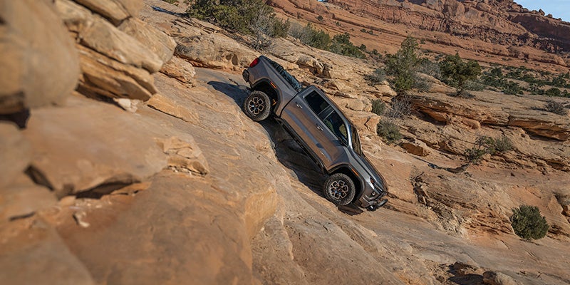 A silver GMC Canyon drives down a rocky hillside
