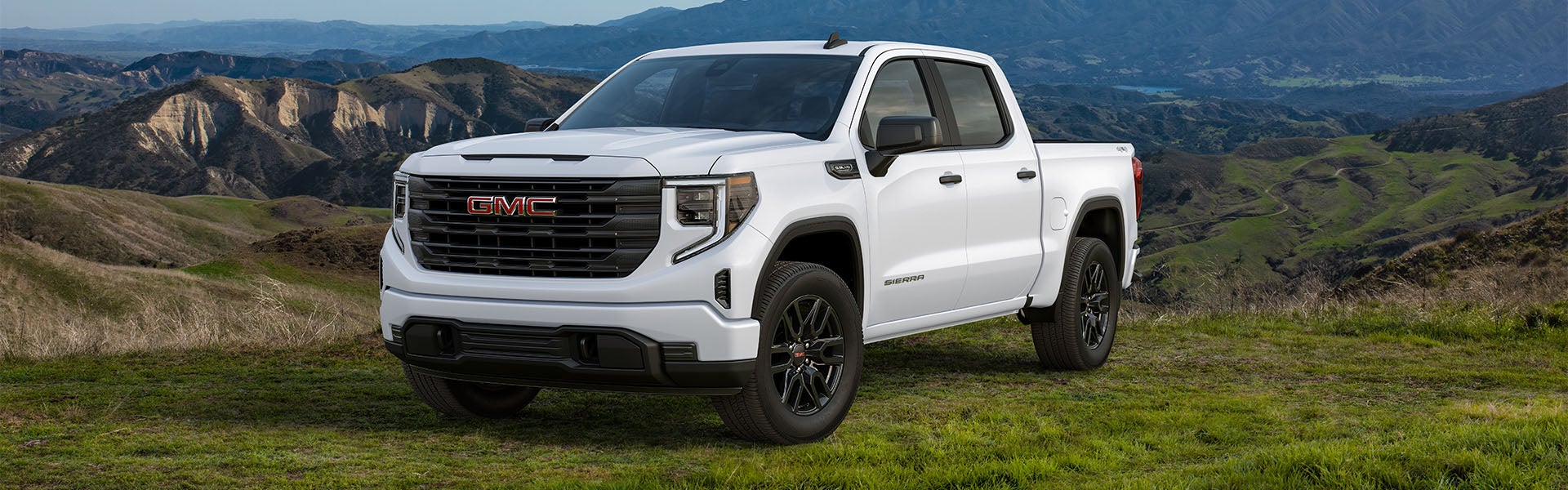 A white GMC Sierra 1500 parked, with mountains the in backdrop
