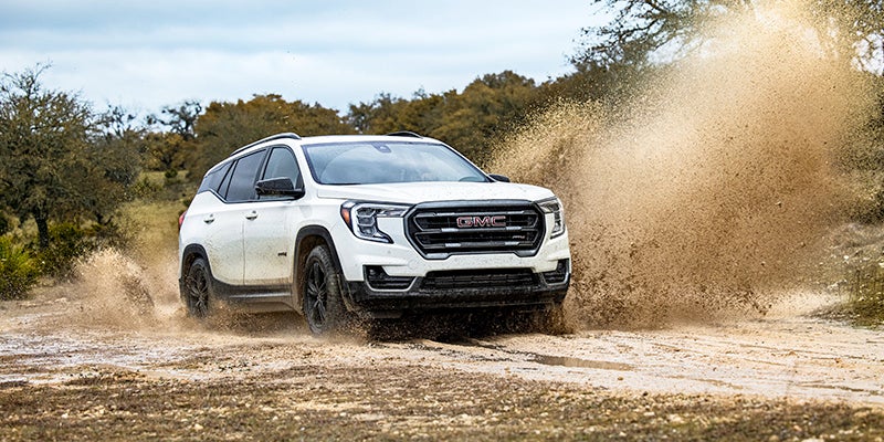 A white GMC Terrain drives through mud